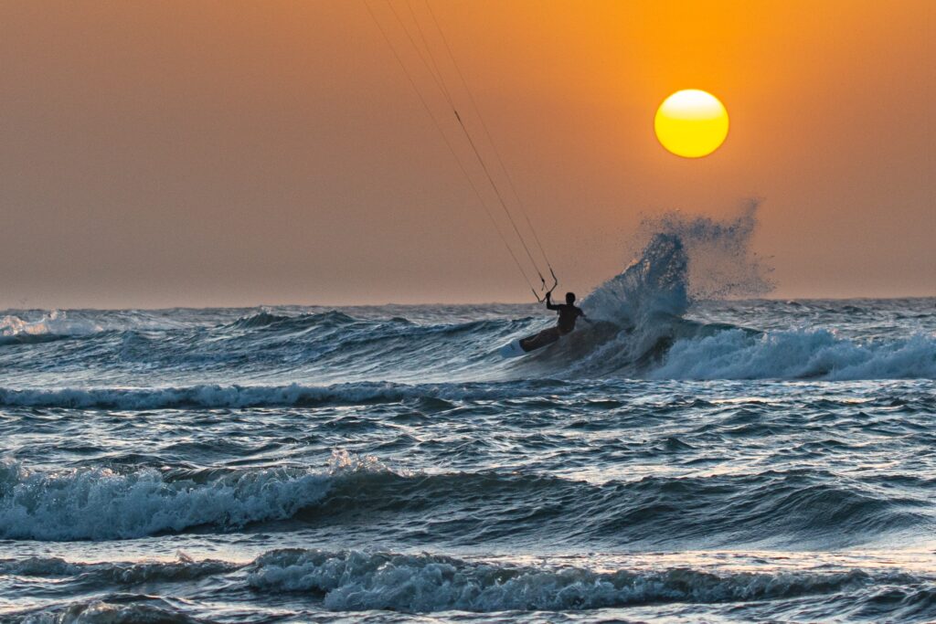 Kite Explorer Colombia - Kite Surf - Colombie - Sur une vague au coucher du soleil, un kkitesurfer terminant son cours avec Kiteexpllorer