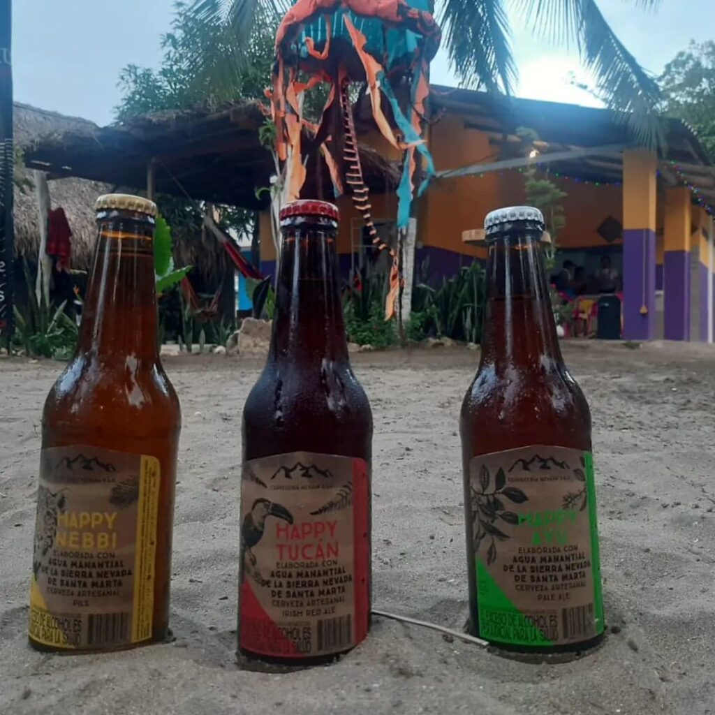 trois bières en bouteille en verre sont posés sur le sable devant le bâtiment de l'école de kite surf kite explorer