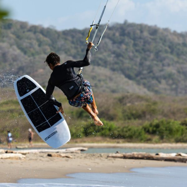 Kite Explorer Colombia - Kite Surf - Colombie - Sur la plage, un élève de kitesurf tient sa voile de la main droite, sa planche strapless de la main gauche et se fait soulever dans les airs