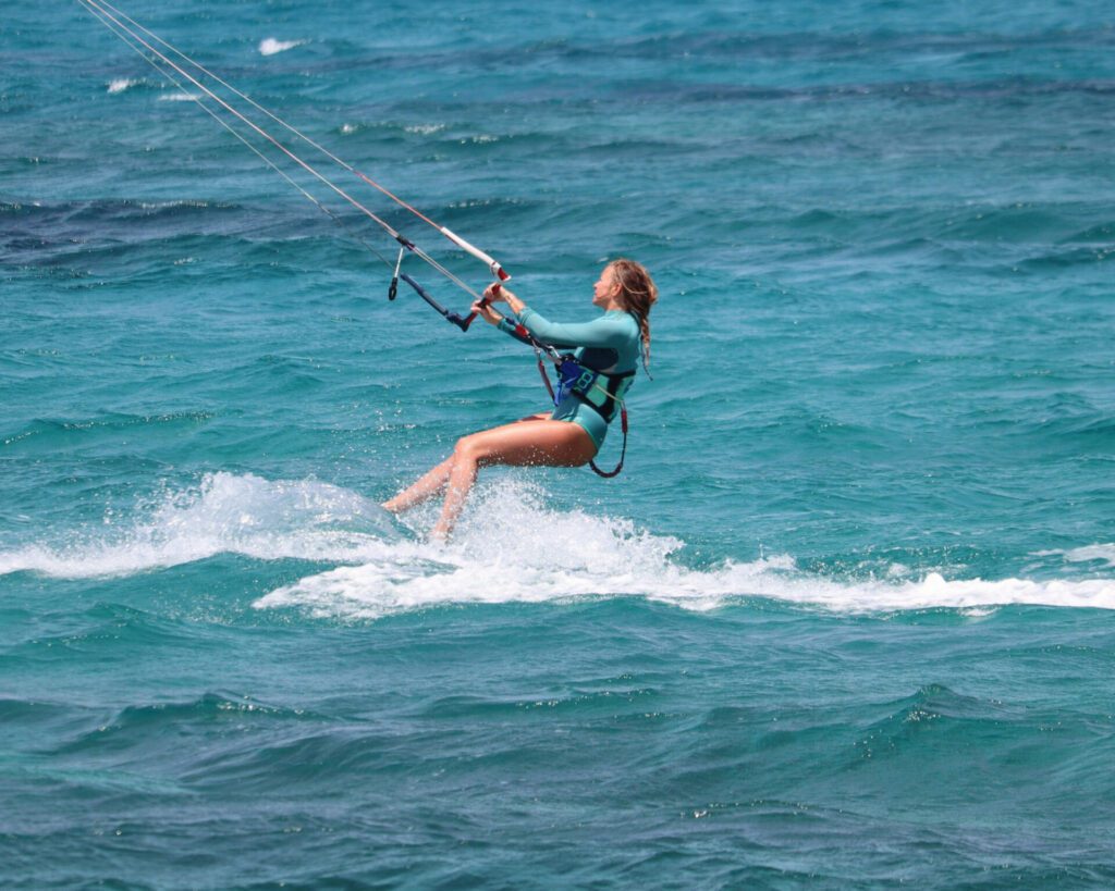 Jeune femme en train de pratiquer le kitesurf en colombie avec kiteexplorer, sur une eau turquoise