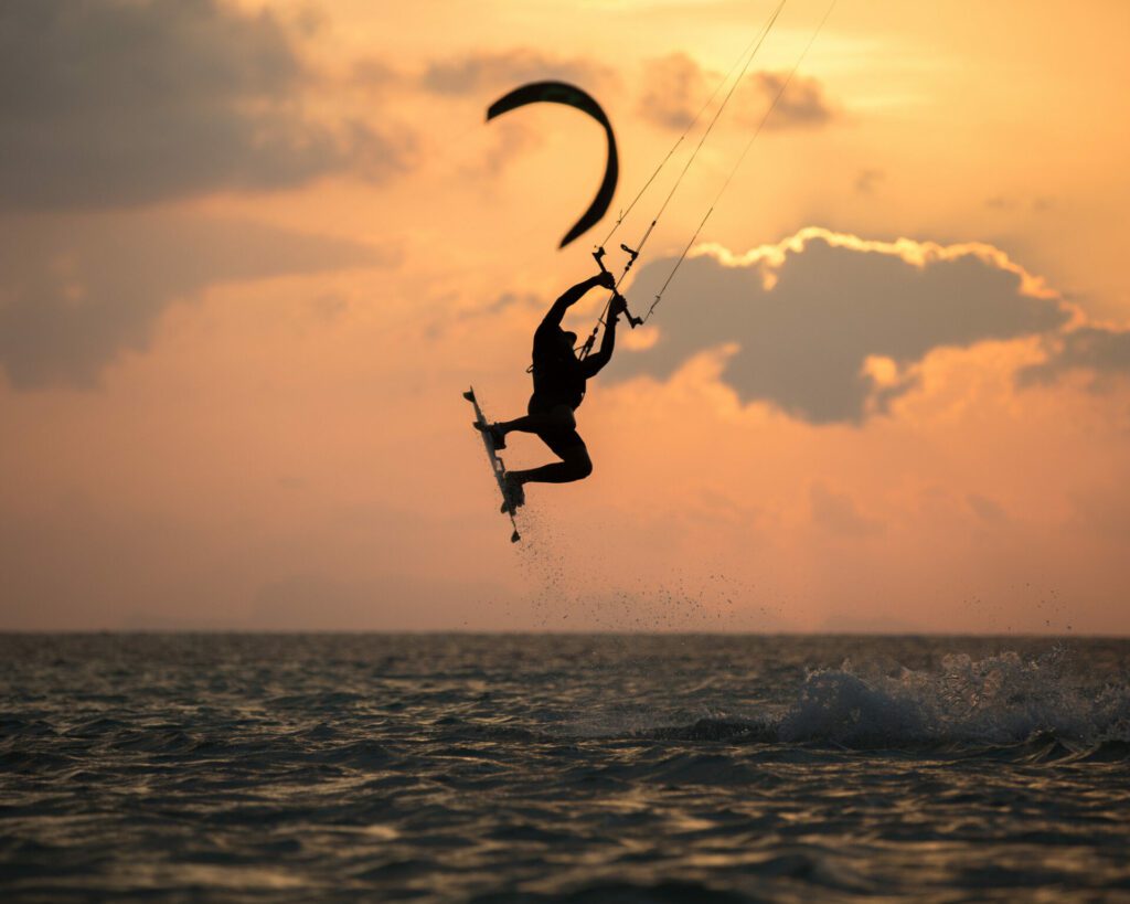 au coucher du soleil, pratiquant de kite surf en train de faire une figure lors d'un saut