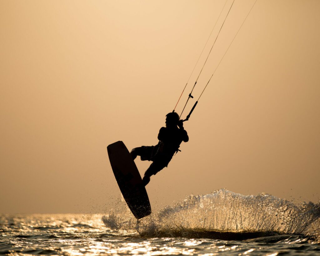 Kite surfeur en train d'effectuer un saut en kitesurf au coucher du soleil